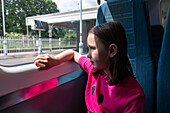 Mädchen (4-5) schaut durch ein Fenster im Zug