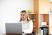 Smiling young female doctor using laptop