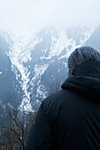 Turkey,  Rear view of man facing mountain covered with snow and fog