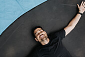 Overhead view of smiling man lying with arms outstretched