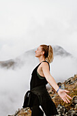 Canada, Whitehorse, Woman with eyes closed and arms outstretched in landscape