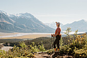 Kanada, Whitehorse, Frau mit Wanderstöcken in Berglandschaft