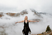 Canada, Whitehorse, Portrait of woman with arms outstretched in foggy landscape