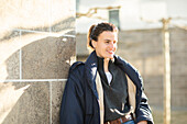 Smiling woman in warm jacket leaning against wall