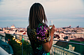 Österreich, Wien, Junge Frau schaut vom Balkon auf das Stadtbild