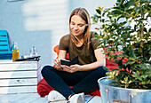 Junge Frau sitzt auf der Terrasse und telefoniert
