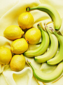 Draufsicht auf Bananen und Zitronen auf gelbem Tuch