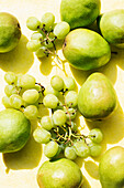 Draufsicht auf Birnen und Trauben auf gelbem Tischtuch