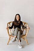 Portrait of smiling young woman sitting in wicker chair