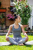 UK, London, Woman meditating on lawn in front of house