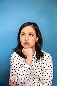 Studioporträt einer gelangweilten Frau vor blauem Hintergrund
