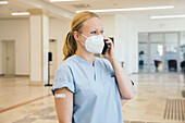 Österreich, Wien, Krankenschwester mit Gesichtsmaske benutzt Smartphone