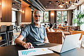 Italien, Porträt eines Geschäftsmannes, der an einem Tisch im Kreativstudio sitzt