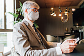 Italy, Businessman in face mask using tablet in creative studio