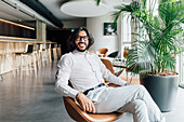 Italien, Porträt eines lächelnden Mannes, der in einem Sessel im Kreativstudio sitzt