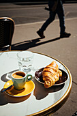 Frankreich, Paris, Croissant, Kaffee und Glas Wasser auf dem Tisch eines Straßencafés