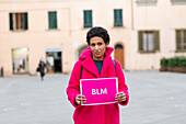 Italien, Toskana, Pistoia, Frau in rosa Mantel hält Schild