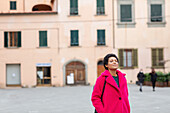Italien, Toskana, Pistoia, Frau im rosa Mantel steht auf dem Stadtplatz