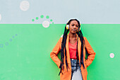 Italy, Milan, Portrait of stylish woman with headphones against wall