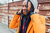 Italy, Milan, Smiling woman in orange coat against rusty metal fence