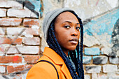 Italy, Milan, Portrait of woman with braids against brick wall