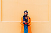 Italy, Milan, Woman in face mask with headphones and smart phone outdoors