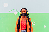 Italy, Milan, Portrait of woman with face mask and headphones against wall