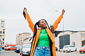 Italy, Milan, Fashionable woman holding face mask and smiling on street