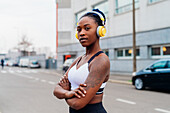 Italien, Mailand, Porträt einer Frau in Sport-BH und Kopfhörern in der Stadt