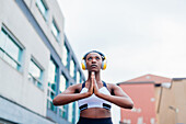 Italy, Milan, Woman with headphones meditating in city