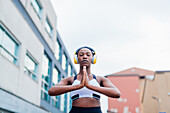 Italy, Milan, Woman with headphones meditating in city