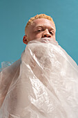 Studioporträt eines in Plastikfolie eingewickelten Albino-Mannes