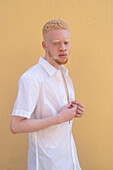 Deutschland, Köln, Albino-Mann in weißem Hemd vor gelber Wand