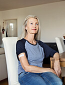 Austria, Vienna, Senior woman with adhesive bandage on arm sitting at table