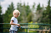 Canada, Ontario, Kingston, Boy (8-9) using water hose