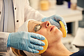 Close-up of beauticians hands cleaning patients face