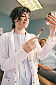 Female doctor preparing botox injection, patient in background