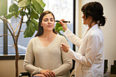 Beautician applying make-up on woman's face