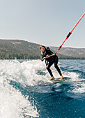Boy (12-13) wakeboarding at lake