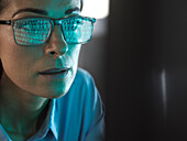 Close-up of programmer with binary code reflected in eyeglasses