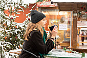 Junge Frau mit Getränk auf dem Weihnachtsmarkt