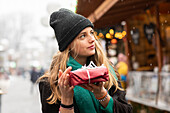 Young woman holding Christmas present outdoors