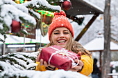 Smiling young woman holding Christmas present outdoors