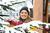 Smiling young woman holding Christmas present outdoors