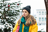 Young woman standing next to Christmas tree outdoors