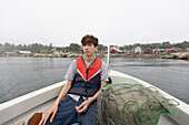 Boy (15-16) sitting in boat on foggy lake