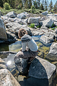 Junge (14-15) spielt auf Felsen am See