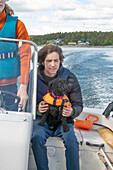 Zwei Jungen (14-15, 16-17) und Hund auf Motorboot