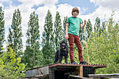 Boy (12-13) and dog standing on shack roof