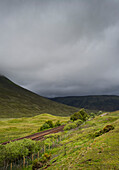 UK, Scotland, Storm clouds above green landscape with railroad tracks